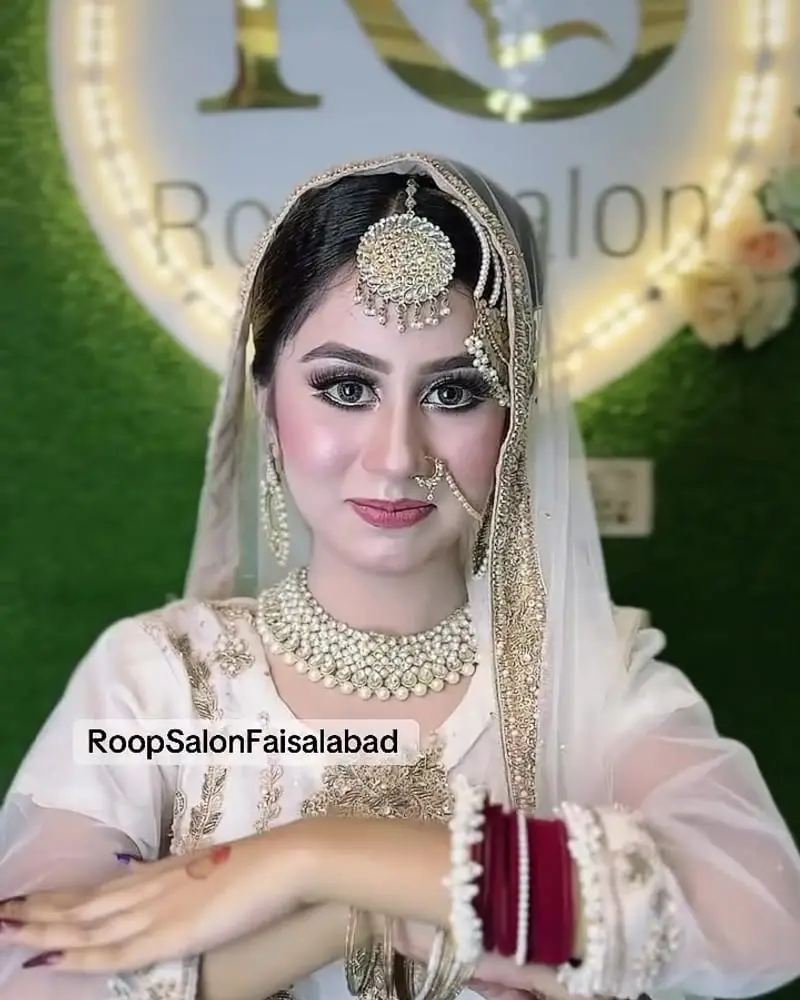 After: the same bride with full bridal makeup, a pearl forehead piece and jewellery