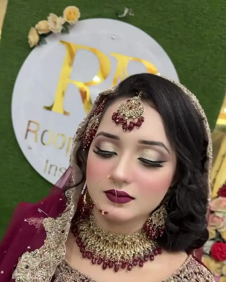 Bride in maroon with bold eye makeup, deep red lips and gold jewellery