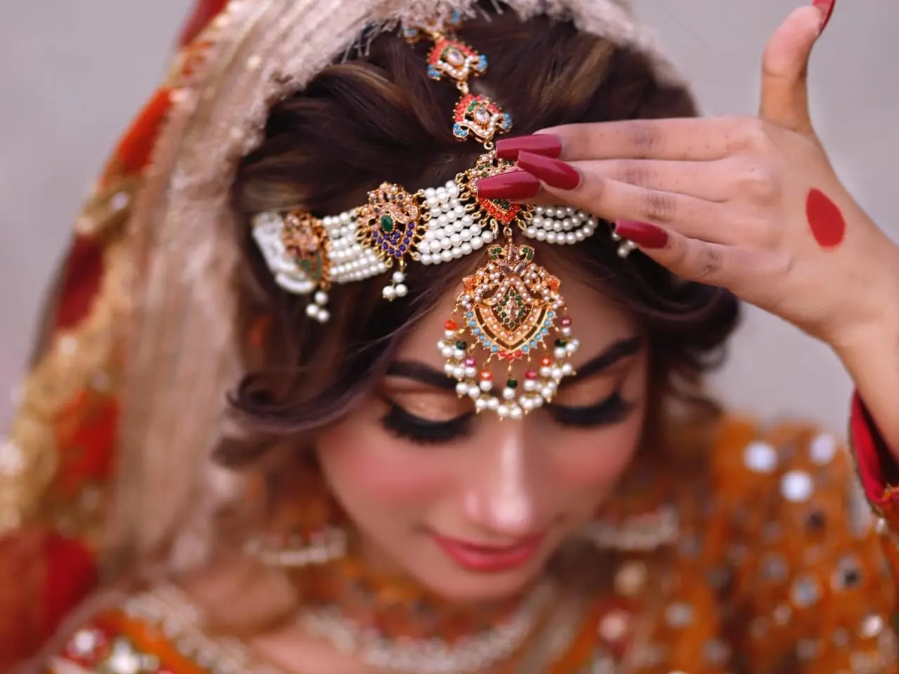 Close-up of a bride with bronze eye makeup, long lashes and a pearl and gemstone matha patti